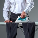 Man ironing black trousers